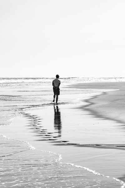 The man walking on the beach during the day
